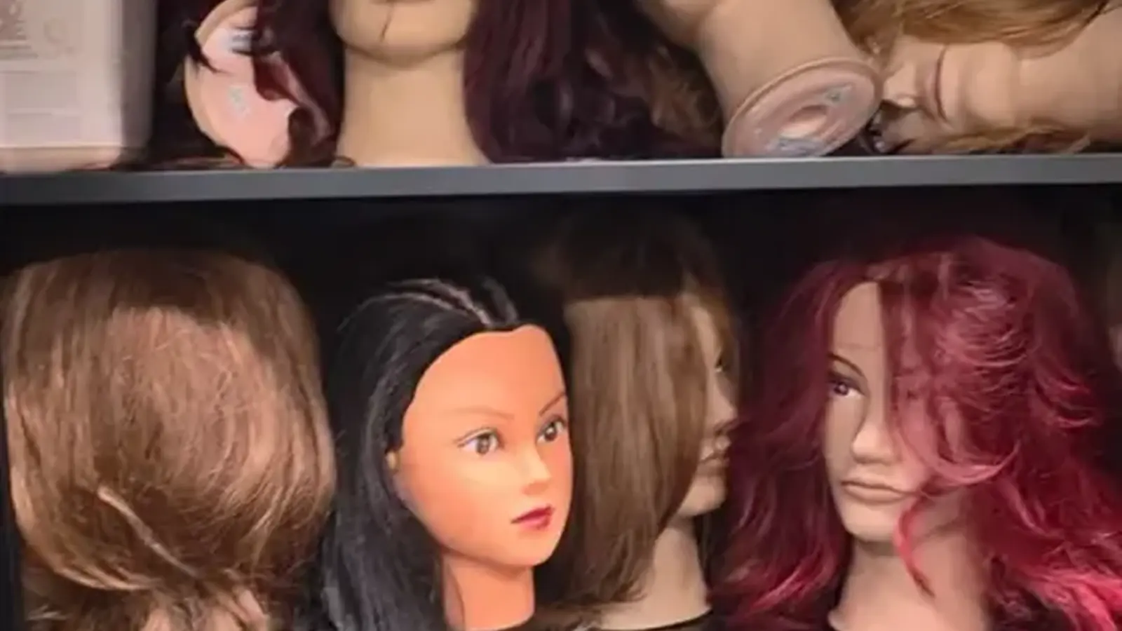 Practice mannequin heads lined up on a salon shelf